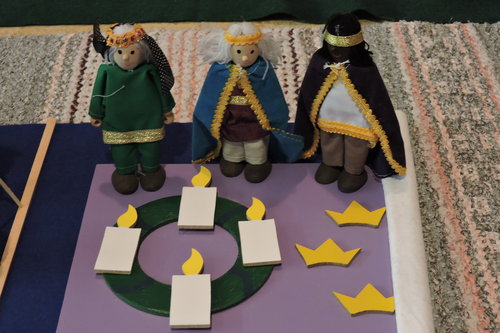 Neljännen adventin neljä kynttilää vihreän ympyrän päällä. Kolme itämaan tietäjä -nukkea. Kolme kruunua.