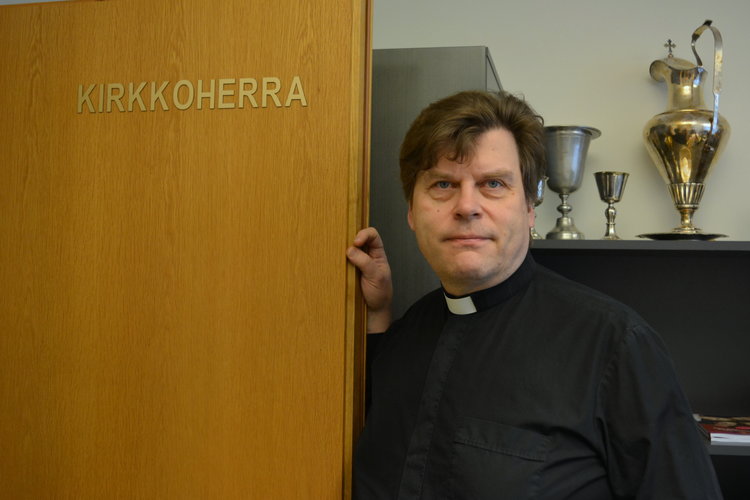 Antti Hiltunen nojaa työhuoneensa oveen, jossa lukee