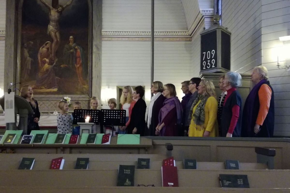 Eri-ikäisiä kuorolaisia laulamassa Anna-kanttorin johdolla.