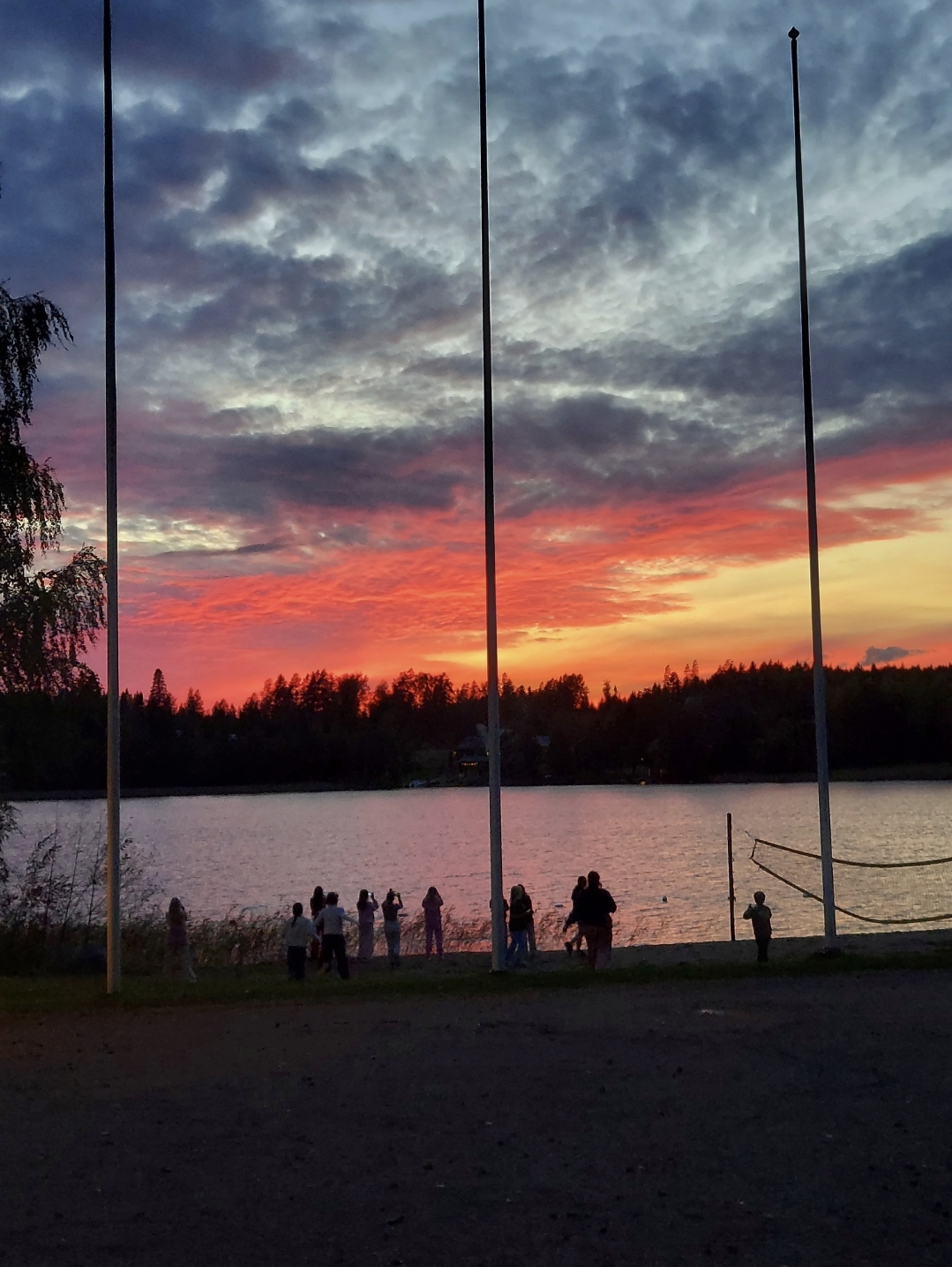 Leiriläiset kuvaavat auringonlaskua Lummeniemen leirikeskuksen rannalla.